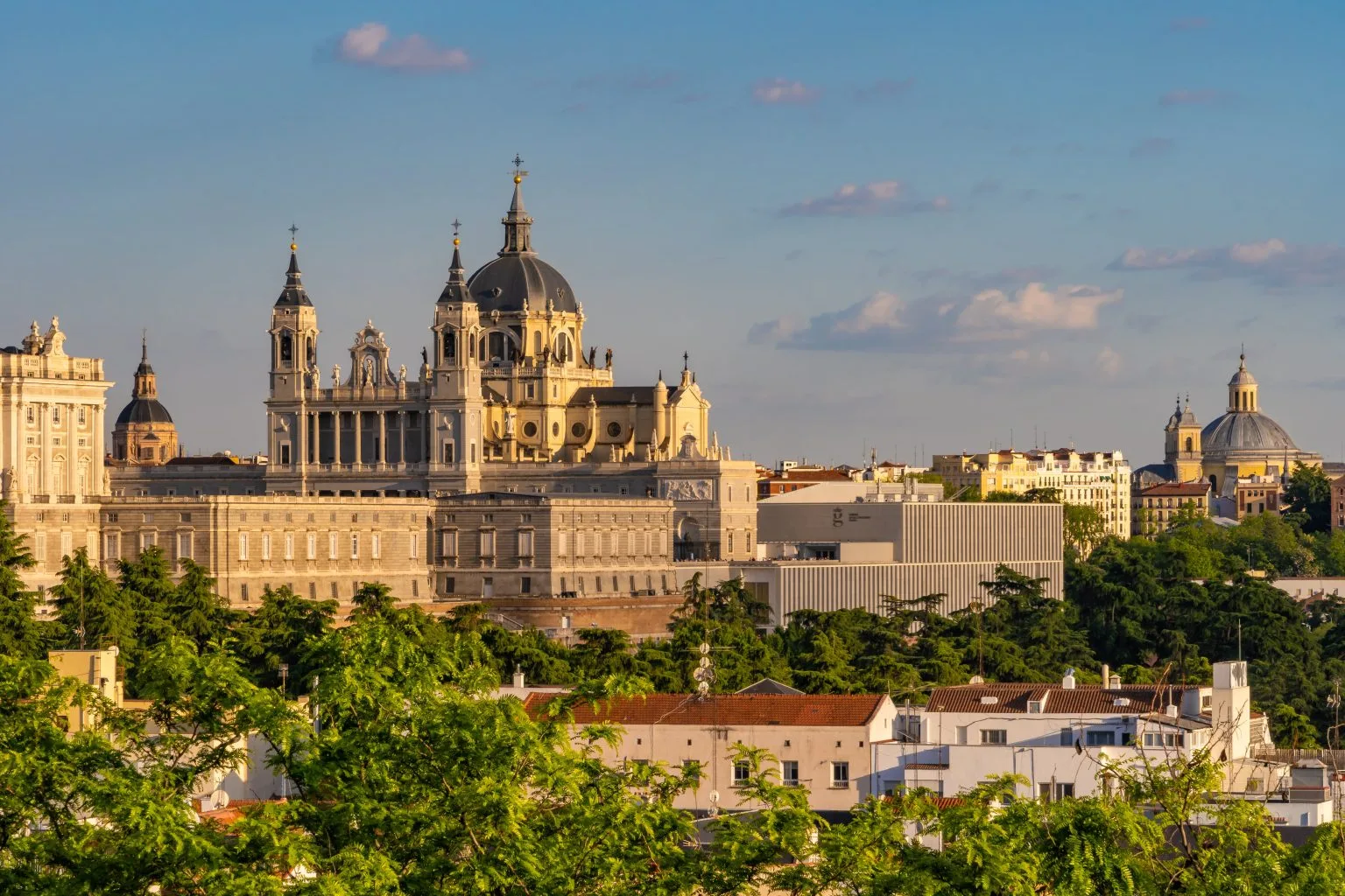 Almudena Cathedral and the Royal Palace above Madrid’s trees in golden light